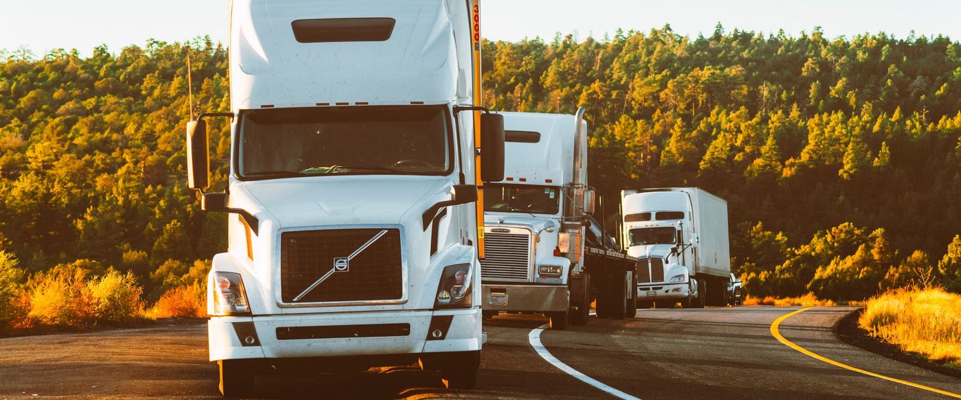 Tractor units running in line on a two-lane highway at first light.