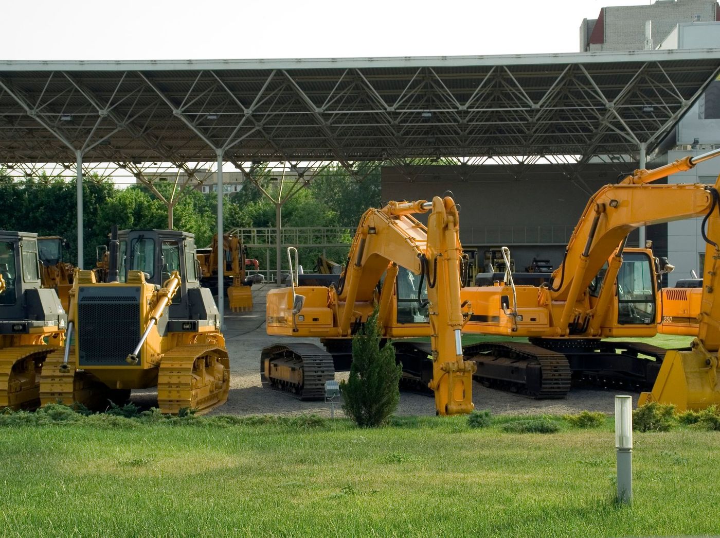 A line of new tracked excavators standing on a dealer lot.